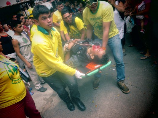 CDS carry the patient towards the ambulance through various passageways of the large Tiendona market.