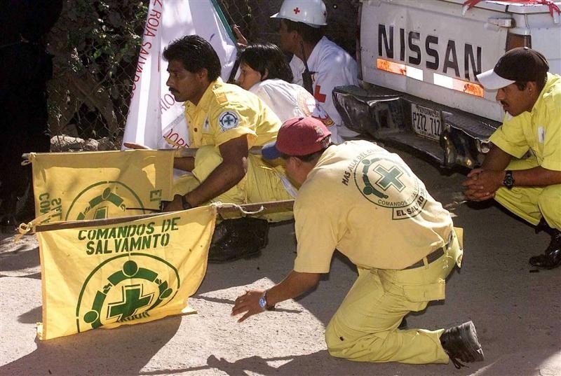 Des secouristes des Comandos se mettent à couvert près d’un pick-up, leurs drapeaux bien visibles.